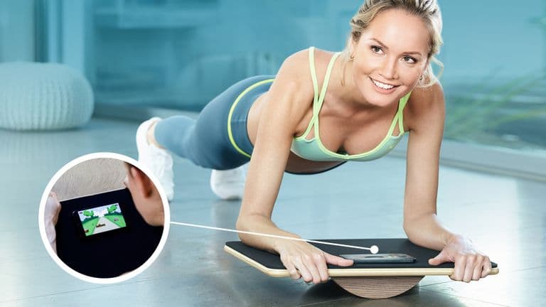 A woman performs a plank on a balance board, using a smartphone app for gamified core training and stability.