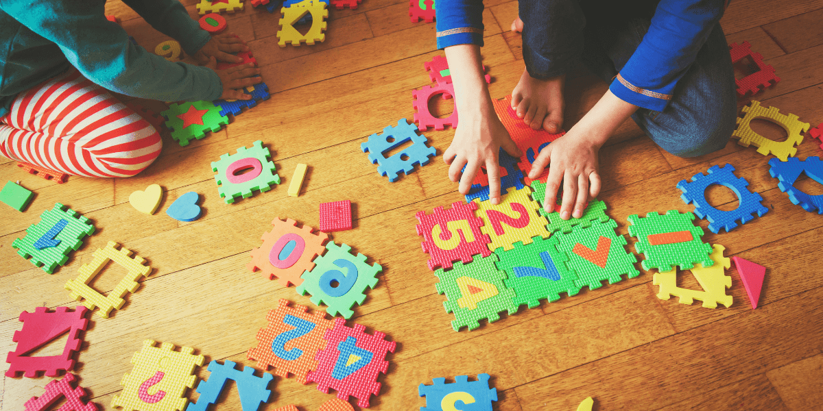 Children playing with colorful foam puzzle pieces on a wooden floor