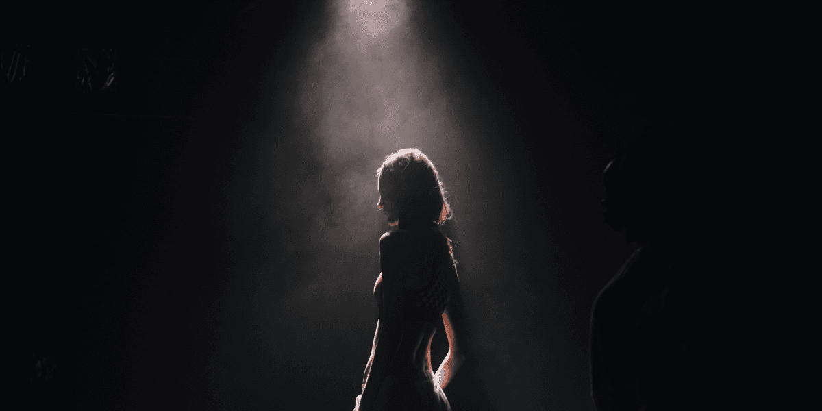 Silhouette of a person illuminated by a spotlight against a dark background