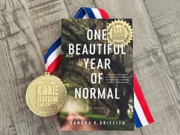 Award-winning novel One Beautiful Year of Normal by Sandra K. Griffith beside an Indie Book Awards medal.