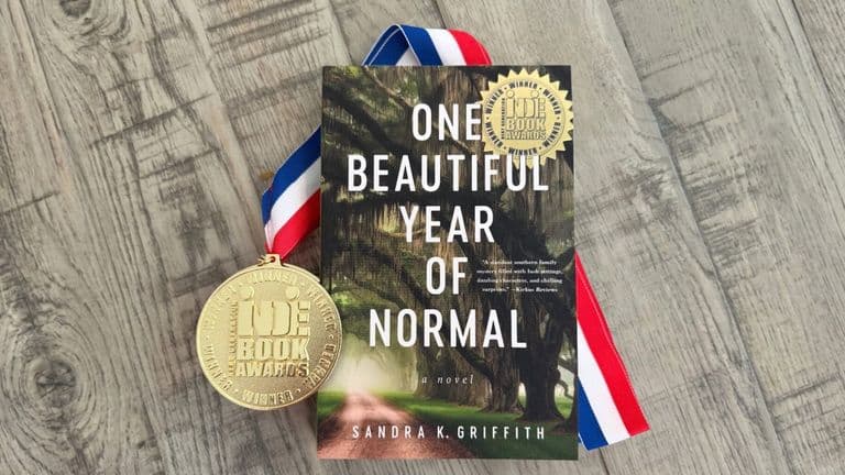 Award-winning novel One Beautiful Year of Normal by Sandra K. Griffith beside an Indie Book Awards medal.