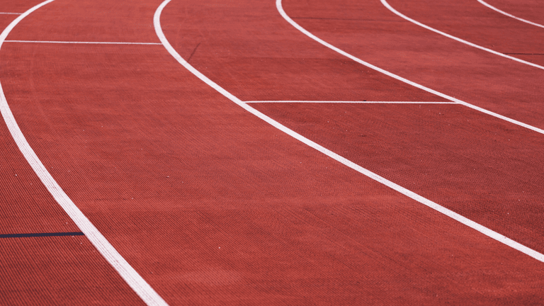 Curved running lanes on a red outdoor track at an athletics stadium.