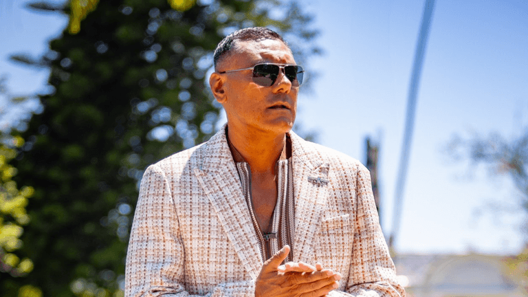 Dylan Garcia, a talented musician and mental health advocate, posing outdoors in a stylish outfit. Known for his unique blend of funk and Neo-Soul, Dylan uses his platform to raise awareness for mental health, encouraging open conversations and supporting individuals through his music and advocacy work