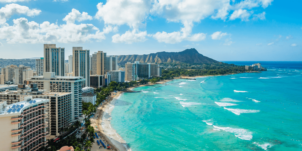Aerial view of a beach with turquoise waters and high-rise buildings in Hawaii