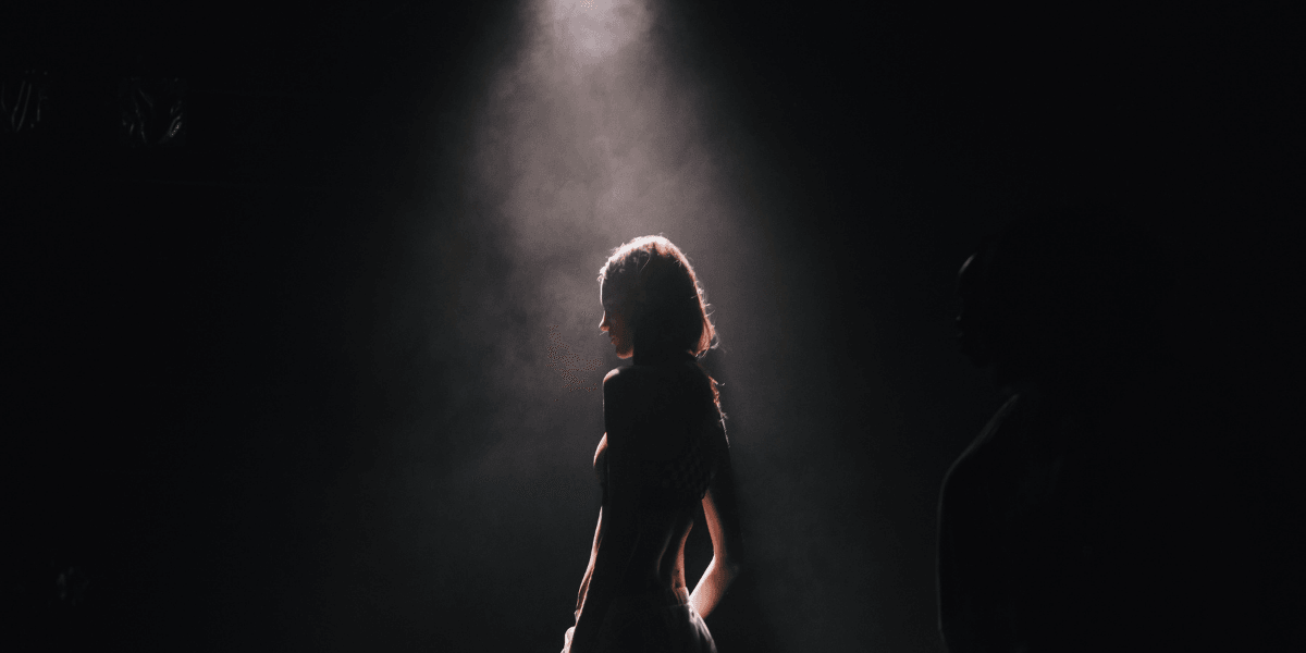 Silhouette of a person illuminated by a spotlight against a dark background