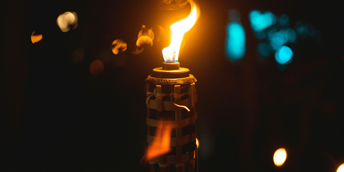 Tiki torch with vibrant flame illuminating the background in a dark setting