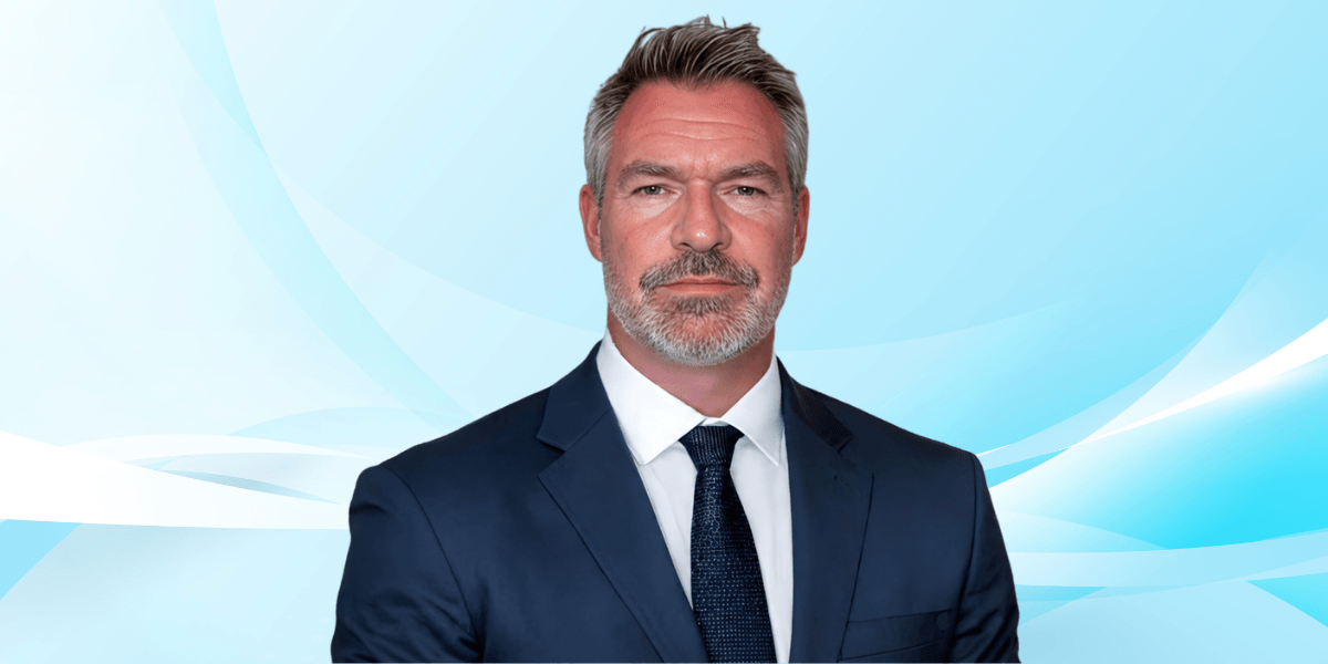 Man in a suit with a serious expression against a light blue background