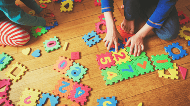 Children playing with colorful foam puzzle pieces on a wooden floor
