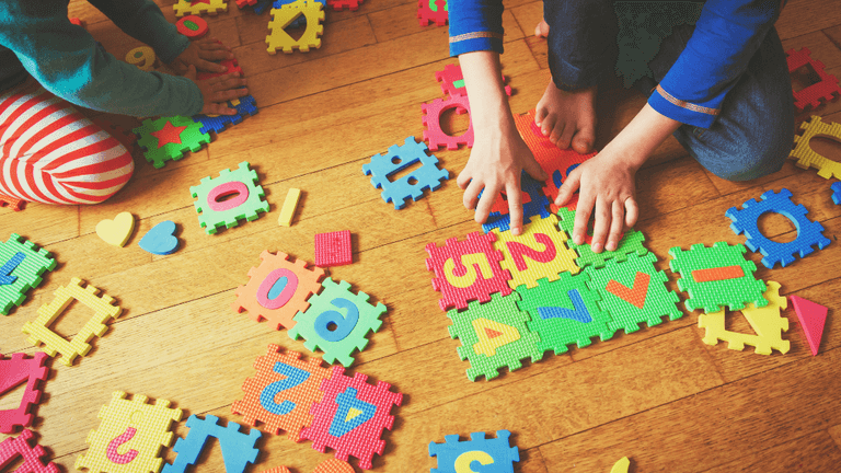 Children playing with colorful foam puzzle pieces on a wooden floor