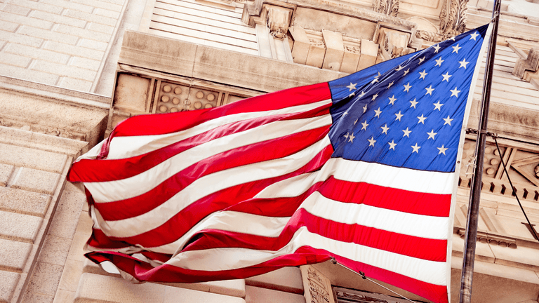Waving American flag with red, white, and blue colors against a stone building