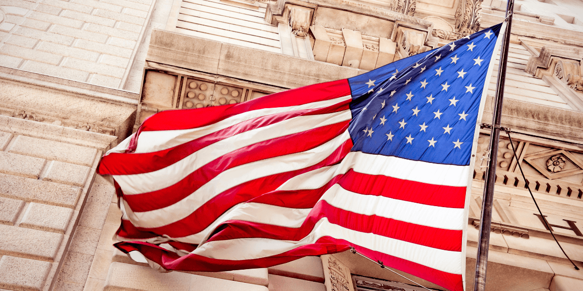 Waving American flag with red, white, and blue colors against a stone building