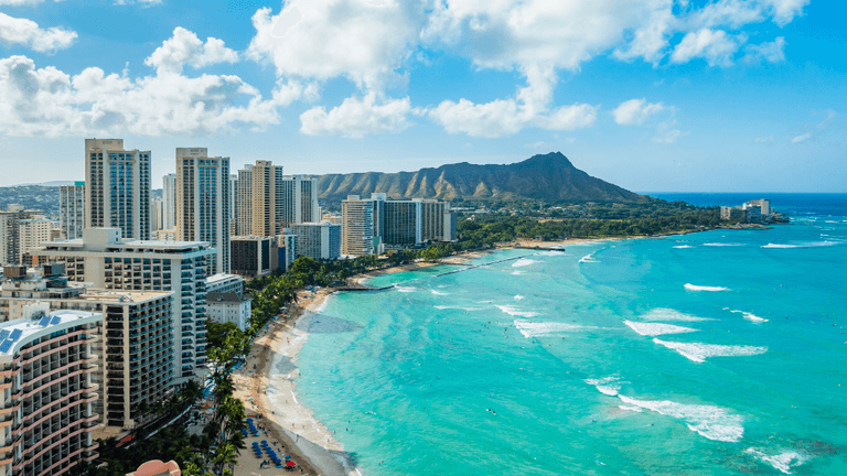 Aerial view of a beach with turquoise waters and high-rise buildings in Hawaii