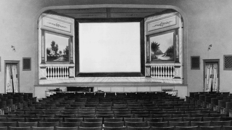 Empty vintage theater interior with a blank screen and rows of wooden chairs