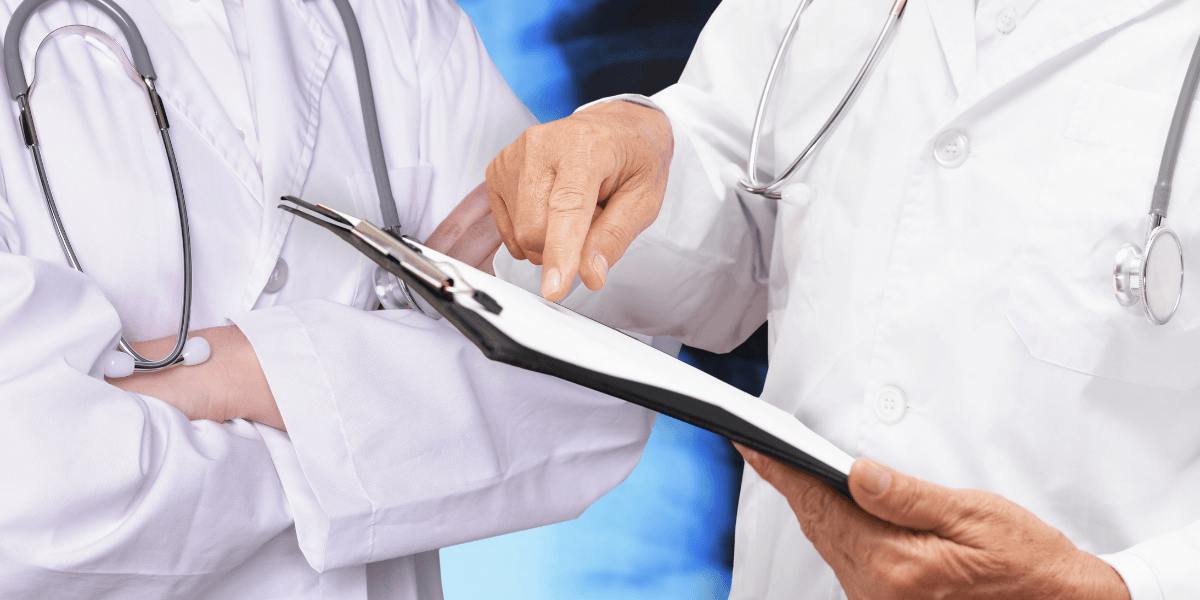Two healthcare professionals discussing a document, one pointing and the other with arms crossed