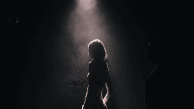 Silhouette of a person illuminated by a spotlight against a dark background