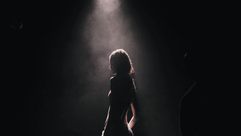 Silhouette of a person illuminated by a spotlight against a dark background