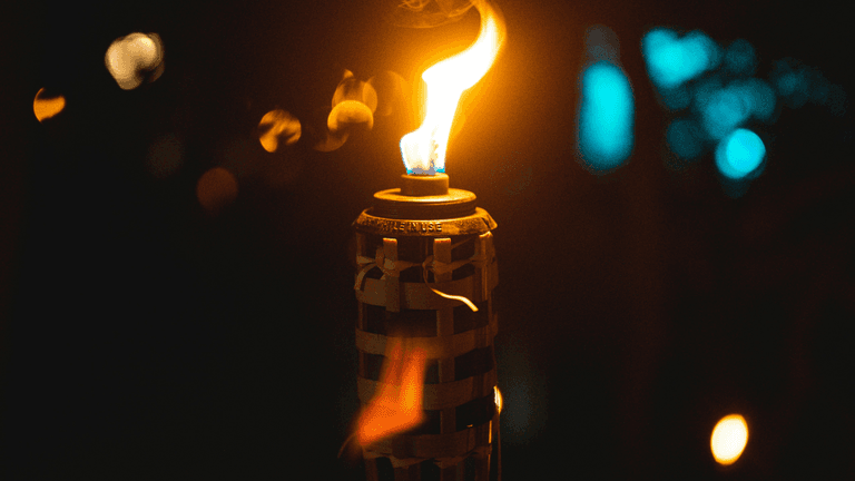 Tiki torch with vibrant flame illuminating the background in a dark setting