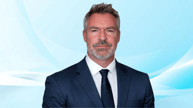 Man in a suit with a serious expression against a light blue background