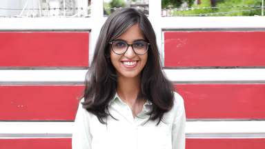 Raj Lakshmi Sharma, a young author, smiling in front of a red and white background, representing her poetry journey.