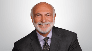 Dr. Michael J. Cooper smiling in a suit, symbolizing his dual roles as physician and peace-focused historical fiction author.