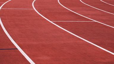 Curved running lanes on a red outdoor track at an athletics stadium.