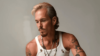 C.J. Shaman, a rising rock and country artist, photographed with a contemplative expression. Known for his raw, rebellious sound and deeply personal music, Shaman combines classic rock energy with modern influences, captivating audiences with his authentic performances and powerful lyrics.