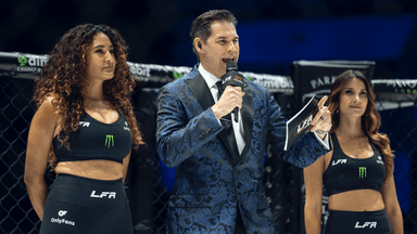Chad Fishburne energetically announcing at a combat sports event with two ring girls, capturing the excitement of the moment.