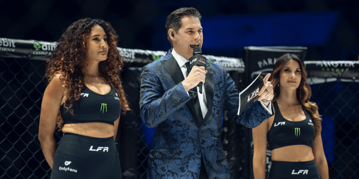 Chad Fishburne energetically announcing at a combat sports event with two ring girls, capturing the excitement of the moment.