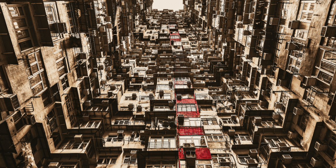 Dense apartment buildings viewed upward, repeating balconies and windows forming abstract inner-city pattern with warm tones.