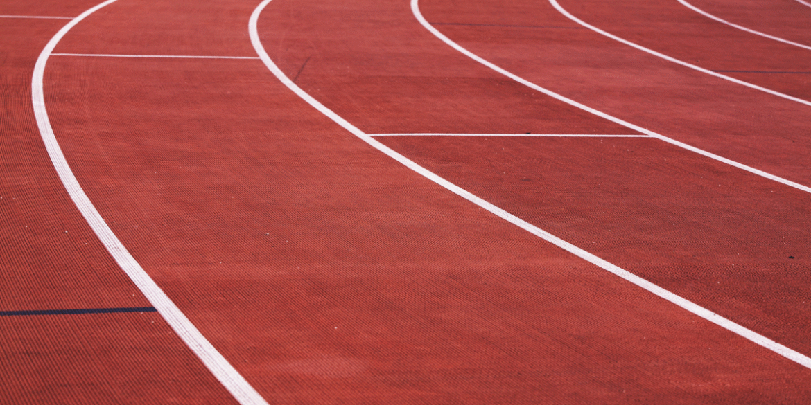 Curved running lanes on a red outdoor track at an athletics stadium.